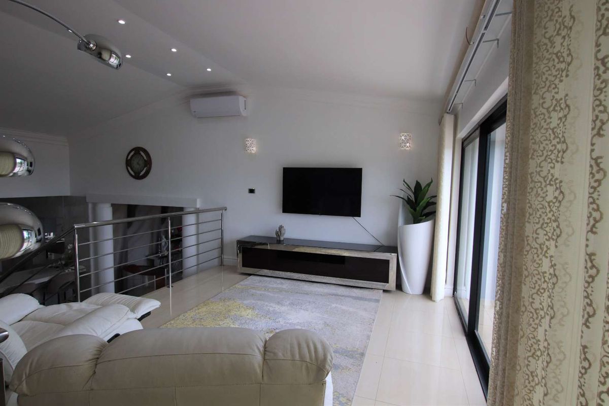 Modern living room featuring tiled flooring, recessed ceiling lighting, a split-system air conditioner, and large sliding glass doors leading to an outdoor area.