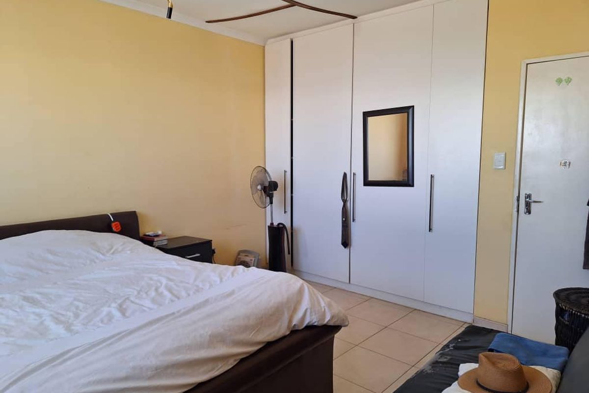 A bedroom featuring built-in white cabinetry and tiled flooring, offering functional storage space and a neutral layout.