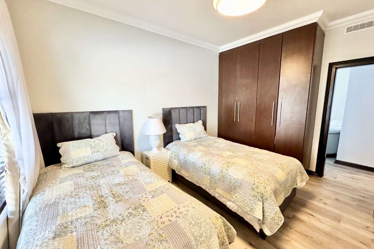 A well-maintained bedroom featuring light wood-look flooring, built-in dark wood cabinetry, and crown molding.