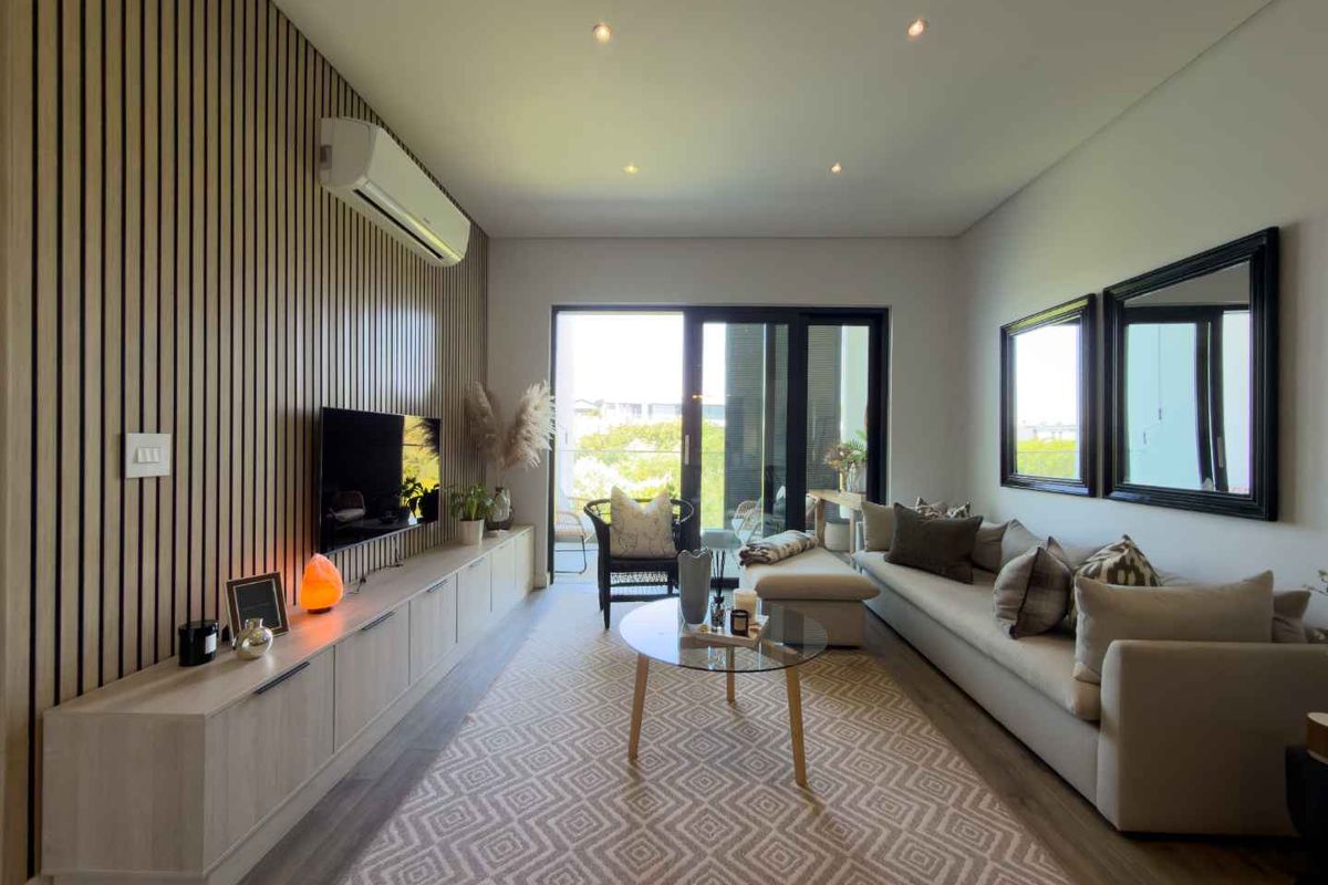 Modern living room featuring a stylish timber slat feature wall, built-in cabinetry, recessed downlighting, and large sliding glass doors leading to a balcony.