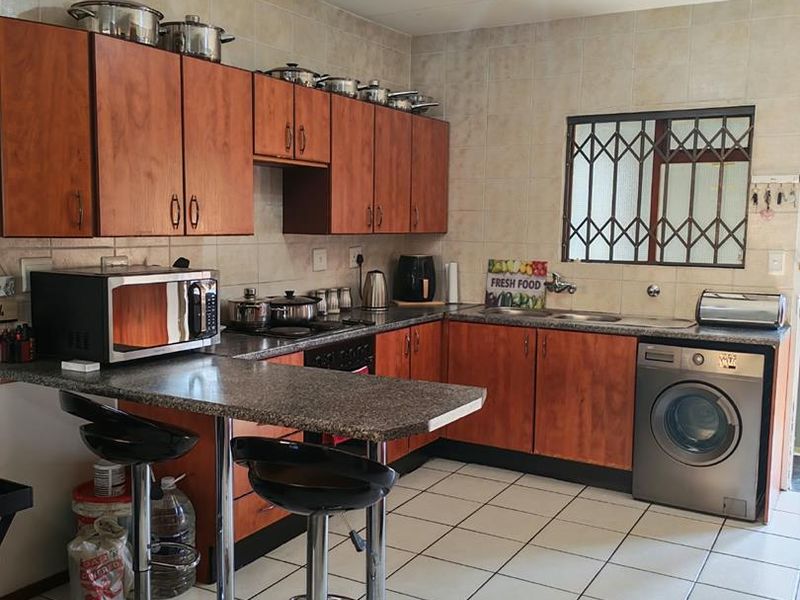 A functional kitchen featuring wood-finish cabinetry, granite countertops, tiled flooring, and a built-in oven with hob, offering a practical layout for daily use.