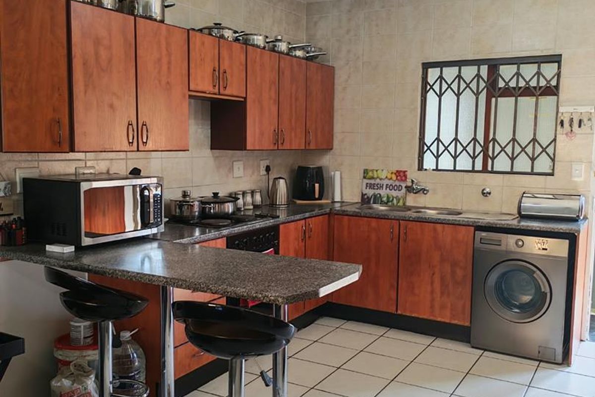 A functional kitchen featuring wood-finish cabinetry, granite countertops, tiled flooring, and a built-in oven with hob, offering a practical layout for daily use.