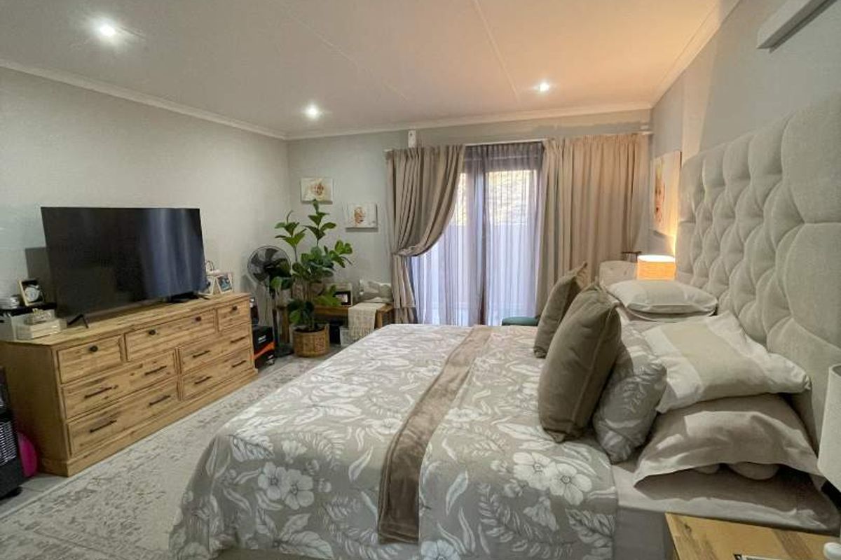 Spacious bedroom featuring tiled flooring, recessed downlighting, and a sliding glass door providing access to the exterior.