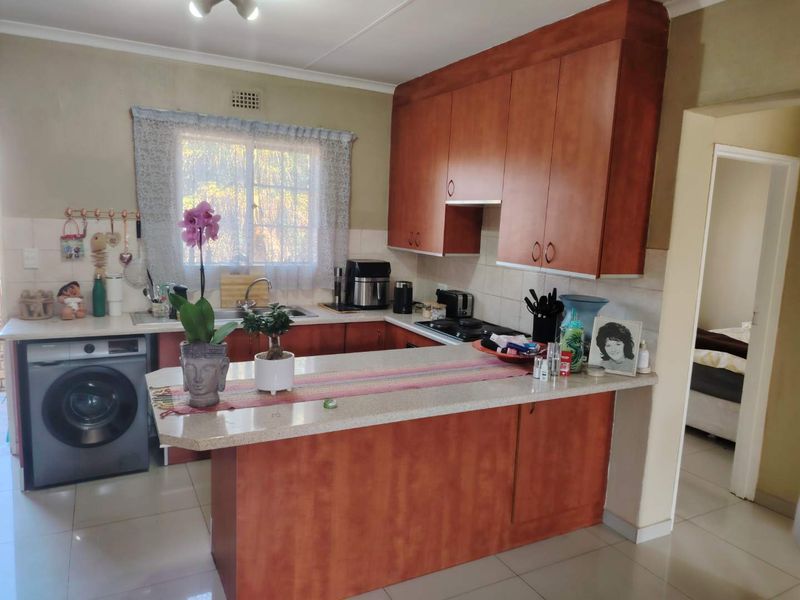 A functional kitchen featuring wooden cabinetry, a breakfast bar, tiled flooring, and a built-in hob, offering a practical layout for daily meal preparation.