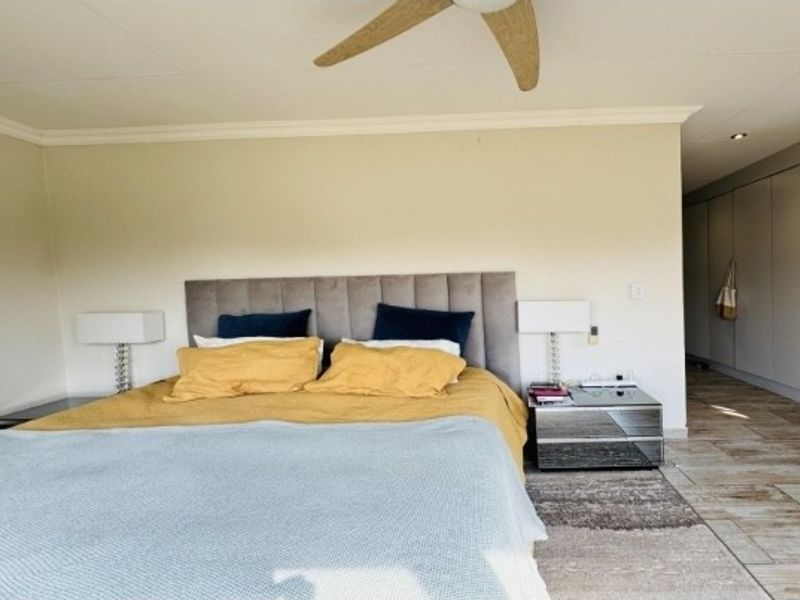 A well-maintained bedroom featuring tiled flooring, a ceiling fan, and extensive built-in cupboard storage.