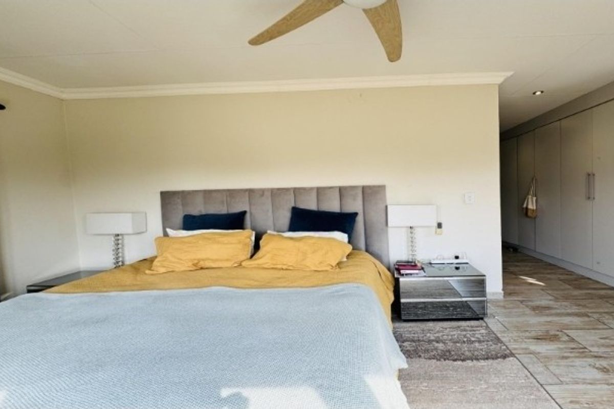 A well-maintained bedroom featuring tiled flooring, a ceiling fan, and extensive built-in cupboard storage.