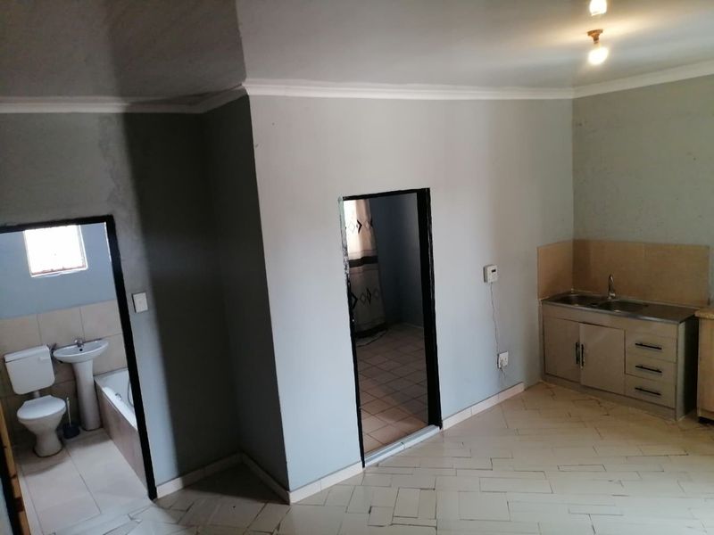 Open plan living area featuring a compact kitchenette and direct access to an adjoining bathroom with standard sanitary fixtures.
