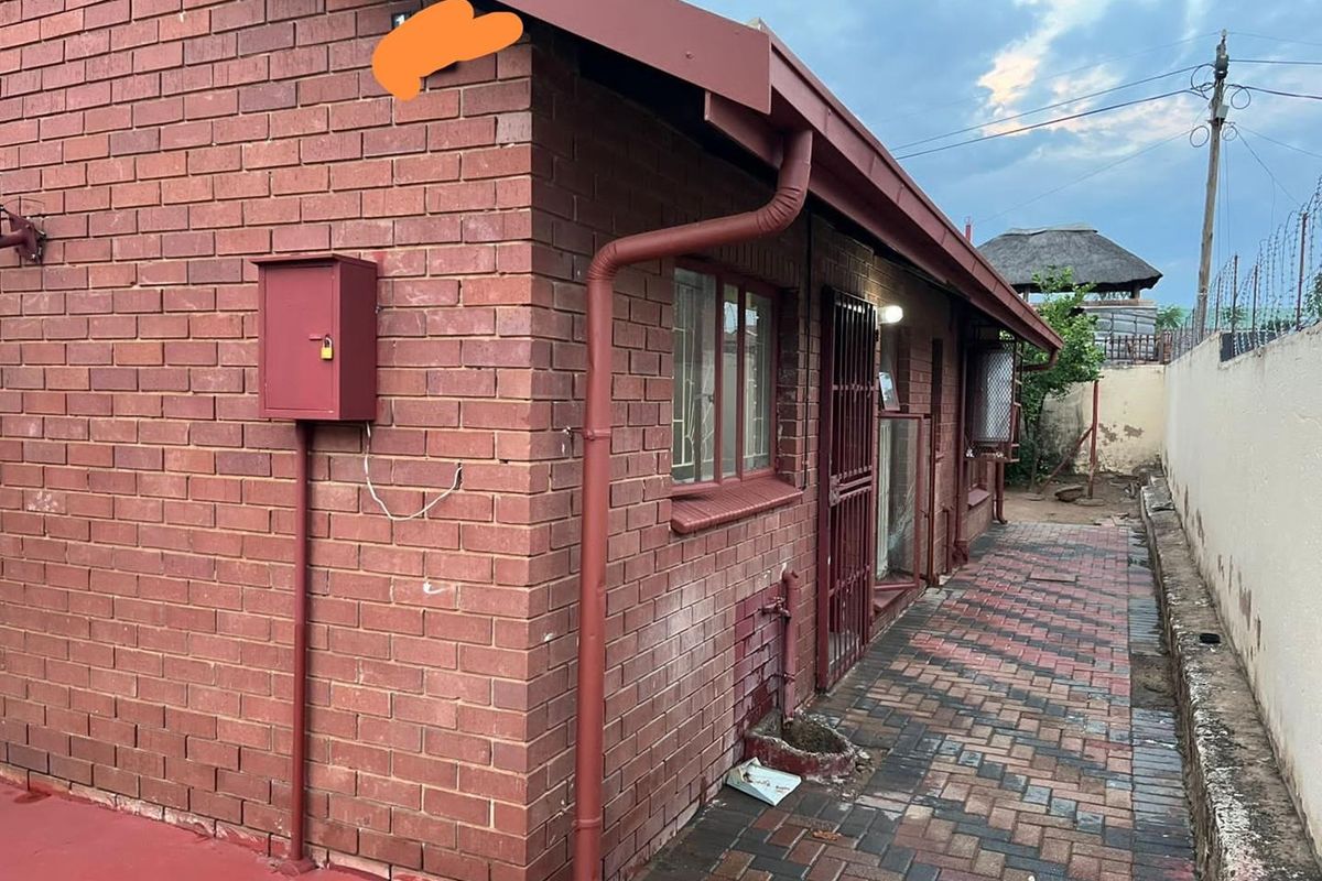 Side exterior view of the house featuring red face-brick walls, paved walkway, and integrated guttering system.