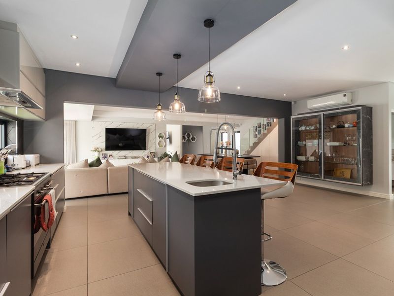 Modern open-plan kitchen featuring a central island with quartz countertops, gas hob, integrated appliances, and sleek cabinetry, flowing into the living area.