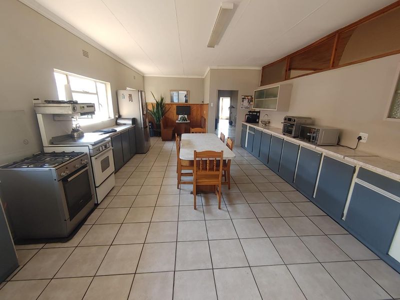 Spacious kitchen featuring extensive built-in cabinetry, gas stove, electric oven, and tiled flooring, offering a functional layout with potential for modern updates.