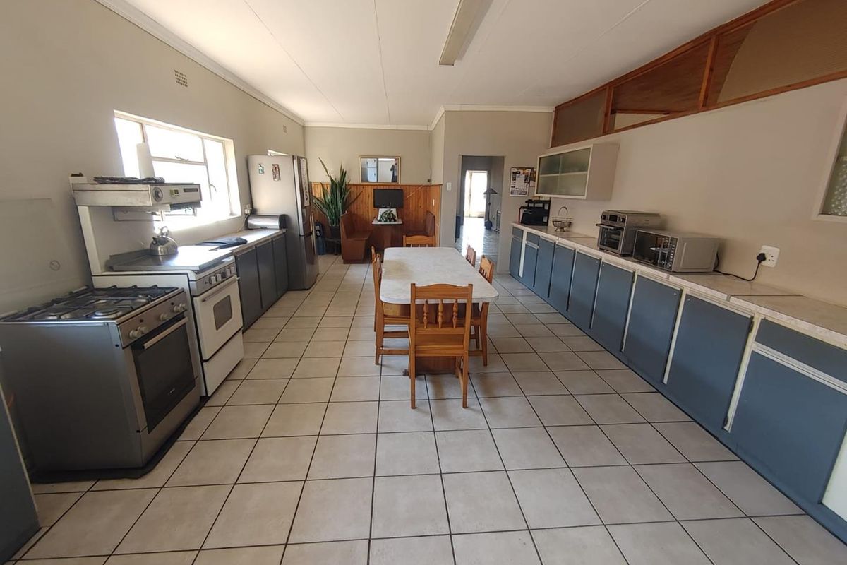Spacious kitchen featuring extensive built-in cabinetry, gas stove, electric oven, and tiled flooring, offering a functional layout with potential for modern updates.