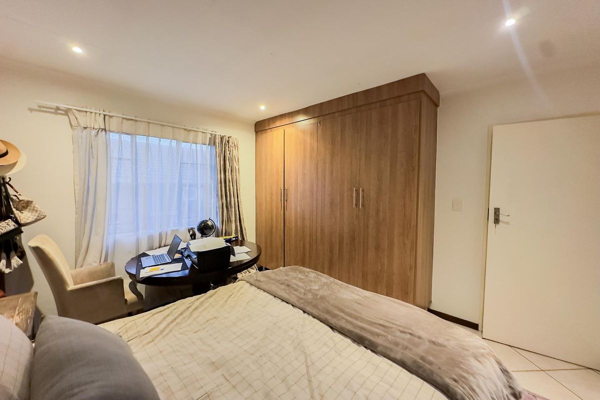 A well-maintained bedroom featuring built-in wooden cabinetry, tiled flooring, and recessed ceiling lighting, offering a functional and comfortable living space.