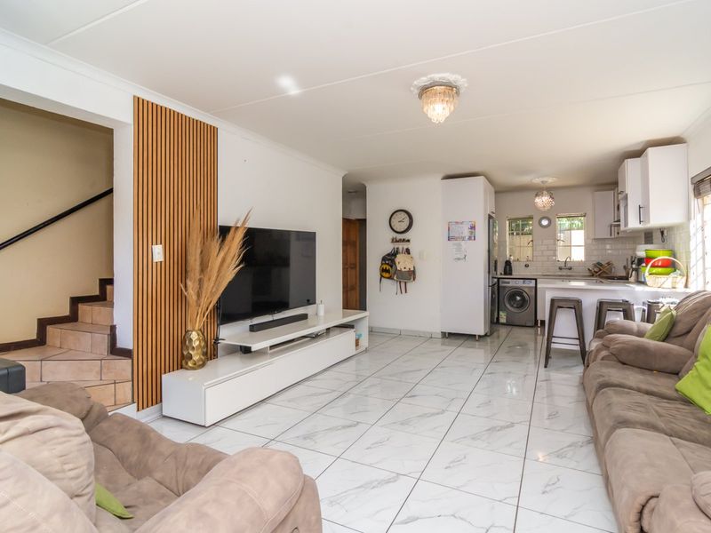 Open-plan living area featuring tiled floors, a decorative slat wall feature, and an integrated kitchen with modern cabinetry and subway tile backsplash.