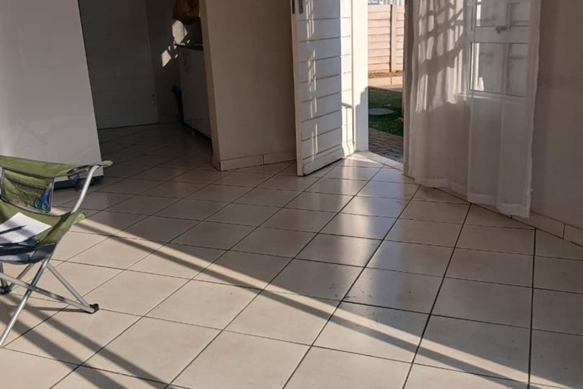 A bright, tiled living area featuring natural light, direct access to the exterior, and neutral wall finishes, offering a clean canvas for interior design.