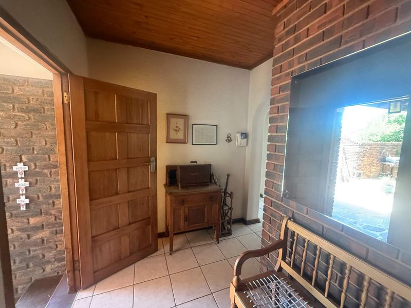 Entrance hall featuring exposed brick walls, timber ceiling, and ceramic floor tiles, providing a warm and rustic welcome to the home.