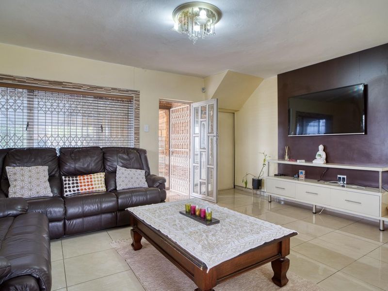 A living room featuring tiled flooring, a decorative ceiling light, and a dark accent wall, providing a functional and comfortable living space.