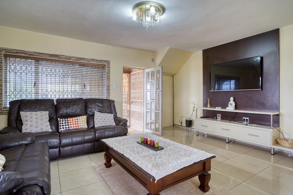 A living room featuring tiled flooring, a decorative ceiling light, and a dark accent wall, providing a functional and comfortable living space.