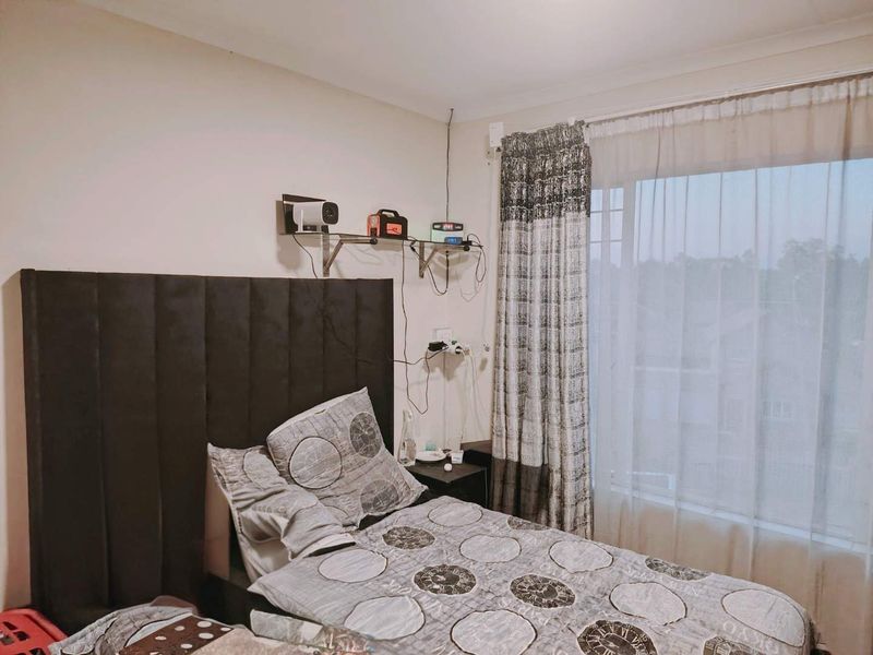 A bedroom featuring a large window with installed curtain tracks, providing natural light and a view of the surrounding area.
