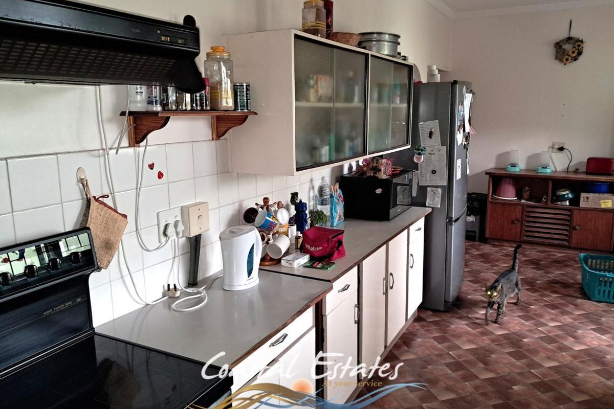 A functional kitchen area featuring built-in cabinetry, a stove with extractor fan, and tiled flooring, offering potential for modernization.