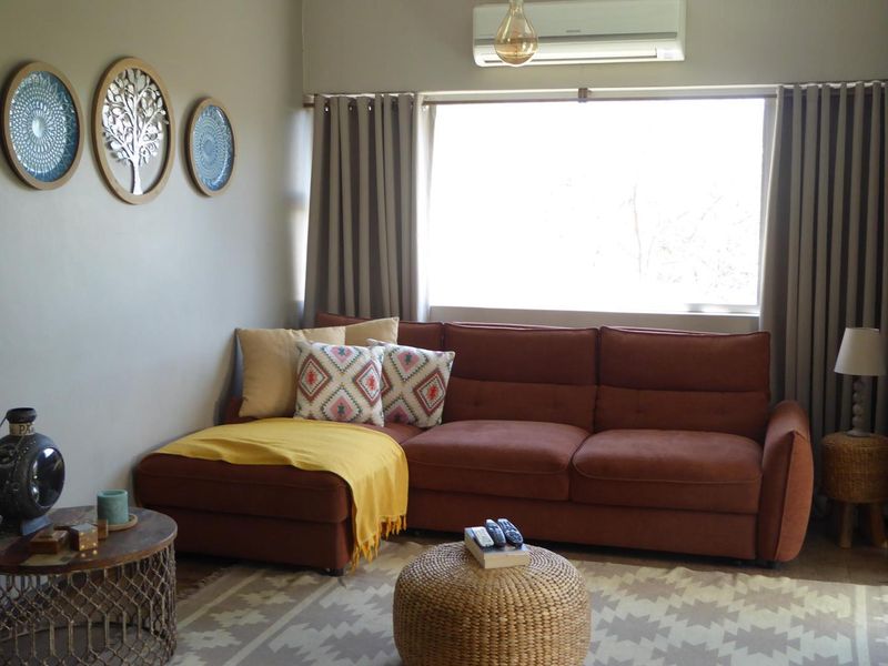 A comfortable living room featuring a large window with curtain tracks and a wall-mounted split-system air conditioning unit.