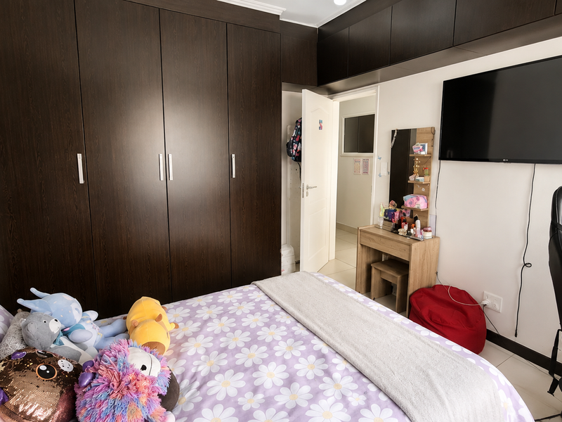 A bedroom featuring extensive dark wood built-in cupboards with overhead storage, providing ample integrated storage space.