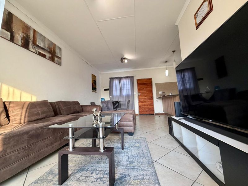 Open-plan living area featuring tiled flooring, a breakfast counter, and direct access to the entrance, creating a functional and connected living space.