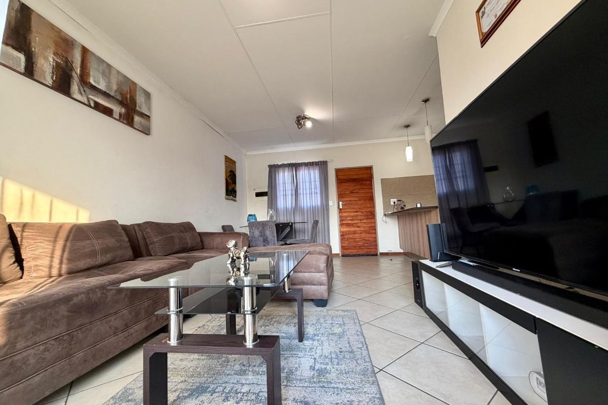 Open-plan living area featuring tiled flooring, a breakfast counter, and direct access to the entrance, creating a functional and connected living space.