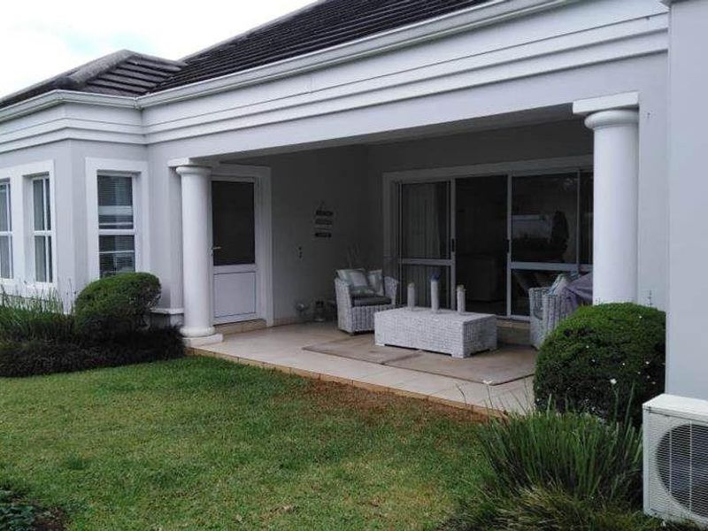 A covered patio area featuring tiled flooring, structural columns, and sliding glass doors providing access to the interior living space.