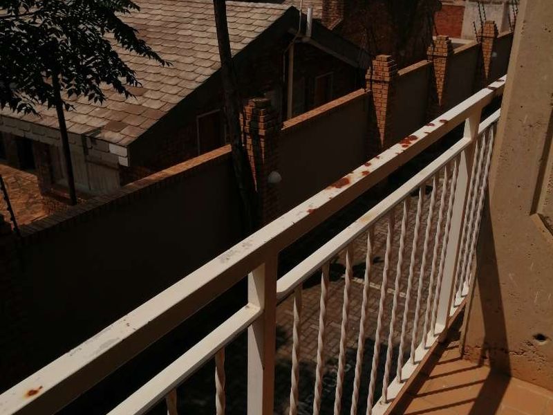 A balcony with tiled flooring and a metal balustrade showing visible signs of corrosion and wear.