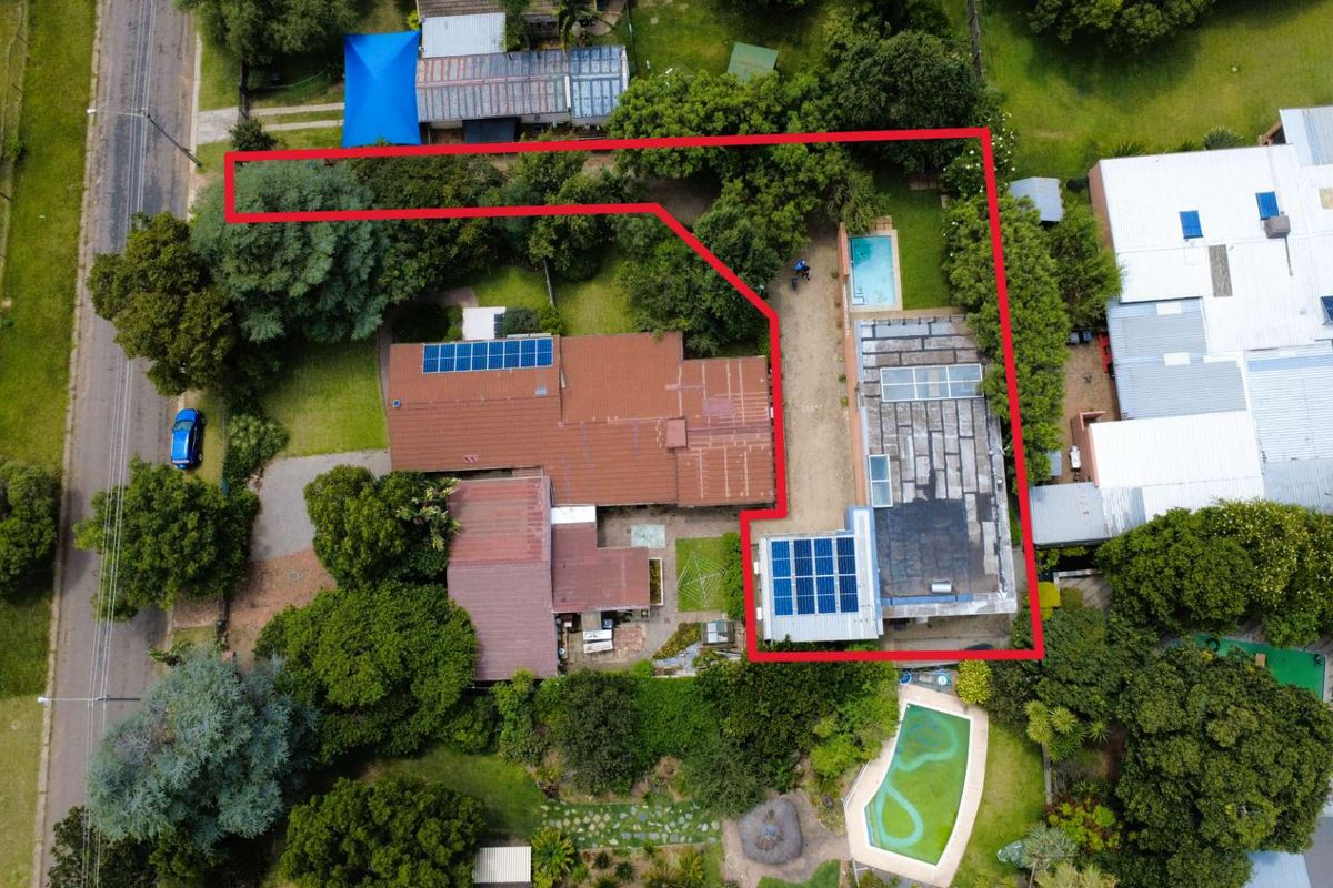 Aerial view of the property showing the main house, swimming pool, landscaped garden, and solar panel installations on the roof.