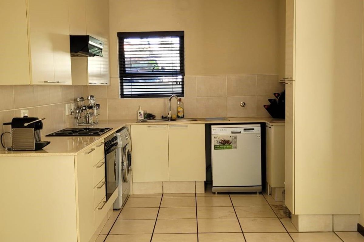 A functional kitchen featuring built-in cabinetry, tiled backsplash, integrated appliances, and tiled flooring, offering a clean and practical workspace.