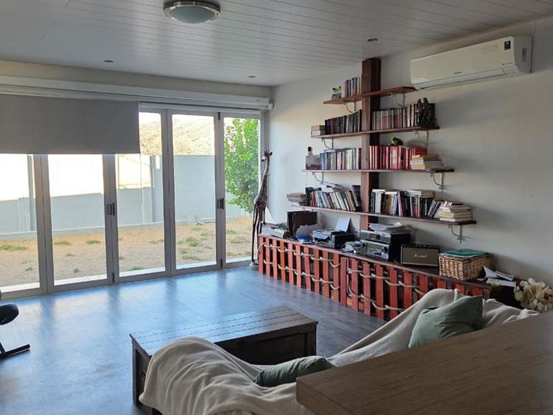 A bright living room featuring modern laminate flooring, timber-look ceiling paneling, and large sliding glass doors that provide direct access to the outdoor area.