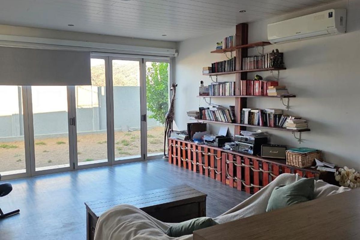 A bright living room featuring modern laminate flooring, timber-look ceiling paneling, and large sliding glass doors that provide direct access to the outdoor area.