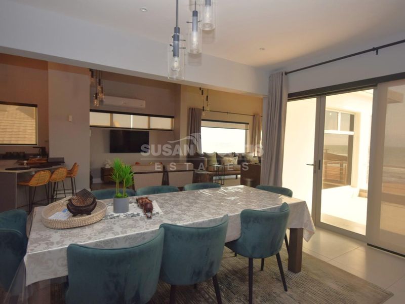 Spacious open-plan living and dining area featuring tiled floors, modern pendant lighting, and large sliding glass doors leading to an outdoor space.