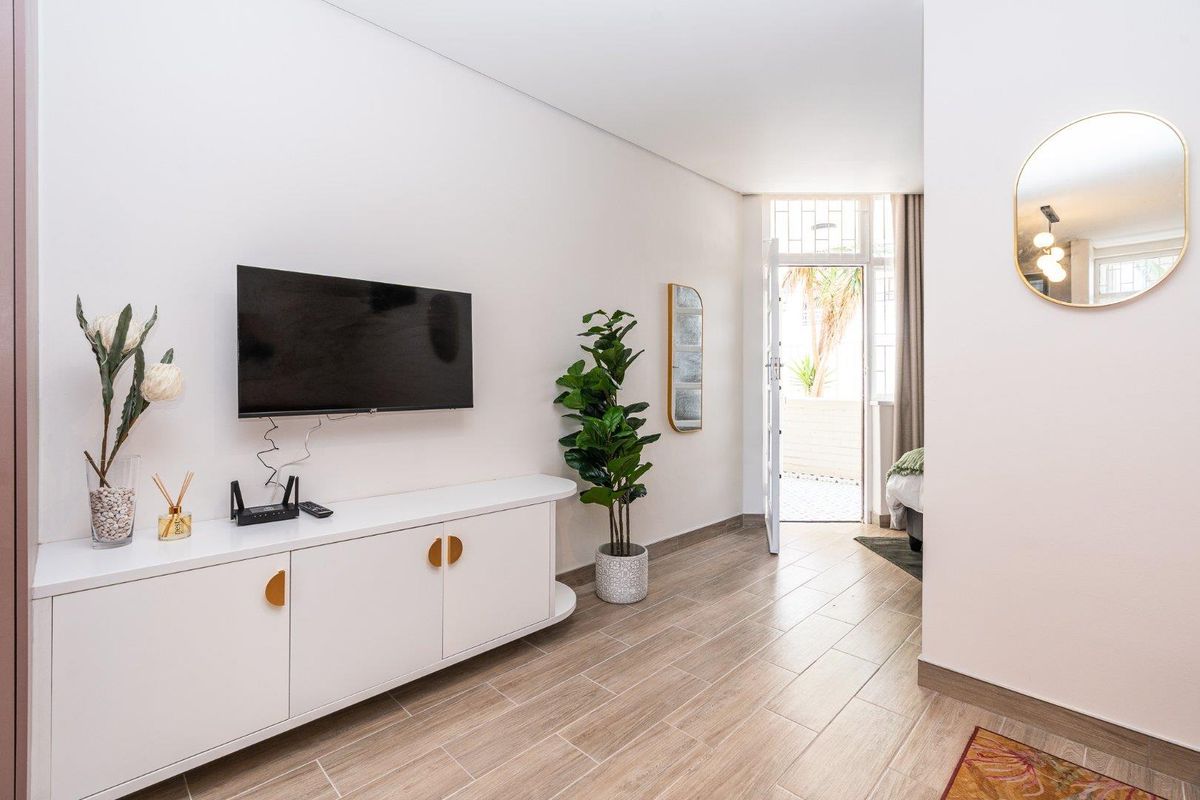 A bright living area featuring modern tiled flooring and direct access to an outdoor space through a secure entrance.