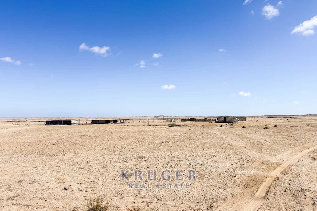 Expansive arid small holding land featuring basic fencing and simple outbuildings, offering vast open space in a remote setting.