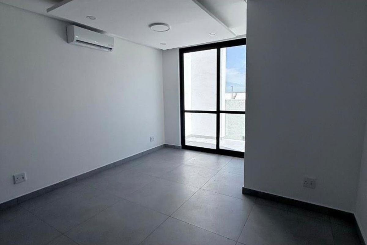 A bright, empty bedroom featuring modern tiled flooring, recessed ceiling lighting, a split-system air conditioner, and a sliding glass door leading to a balcony.