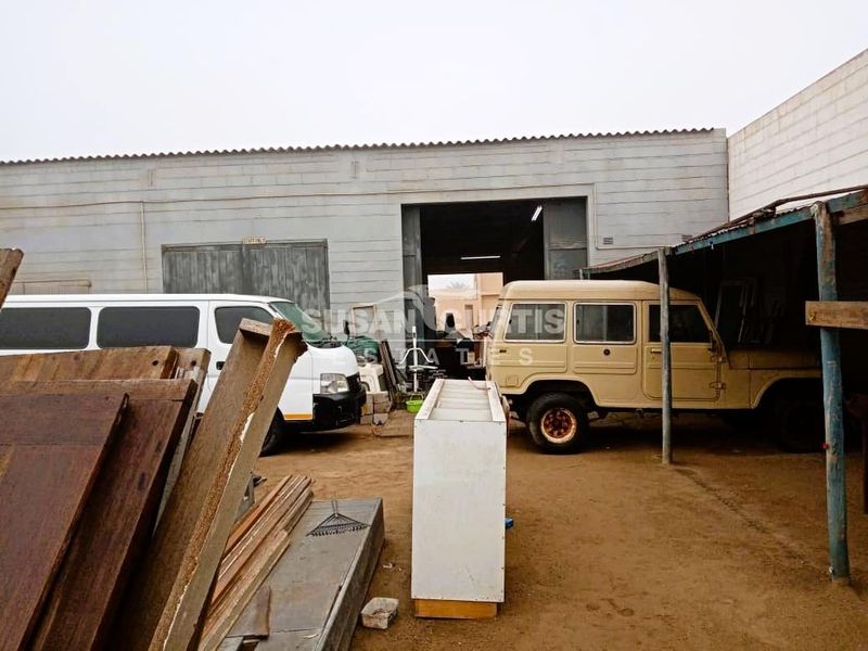 Industrial rear yard area featuring a large roller shutter door, covered loading bay, and concrete block construction.