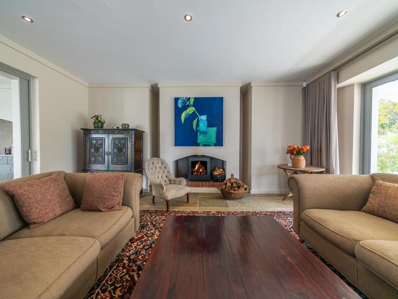 A comfortable living room featuring a built-in fireplace, stone flooring, and large sliding glass doors that provide natural light and garden access.