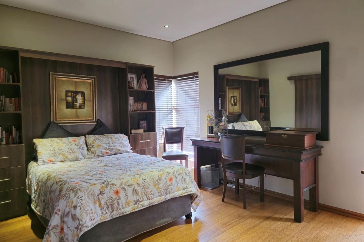 A well-maintained bedroom featuring custom built-in headboard cabinetry, laminate flooring, and recessed lighting, offering a functional and organized living space.