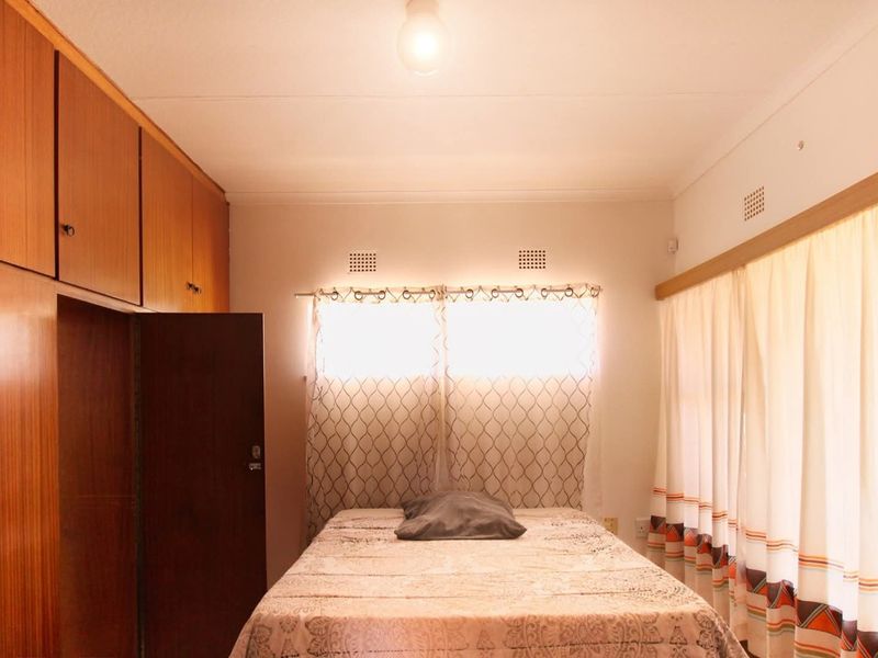 A bedroom featuring extensive built-in wooden cabinetry and natural light through curtained windows.
