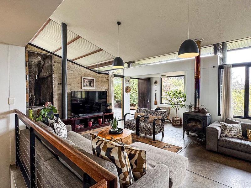 Spacious living room featuring exposed brick walls, concrete flooring, a wood-burning stove, and large windows providing ample natural light.