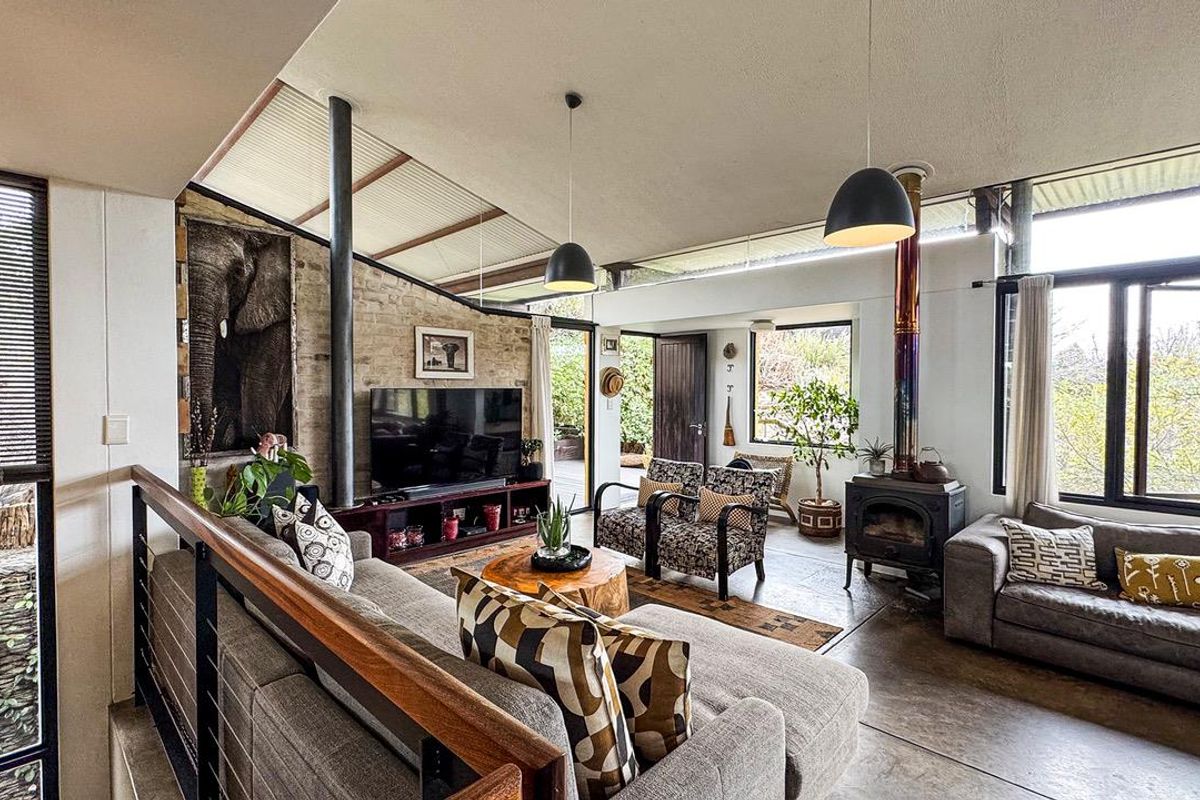 Spacious living room featuring exposed brick walls, concrete flooring, a wood-burning stove, and large windows providing ample natural light.