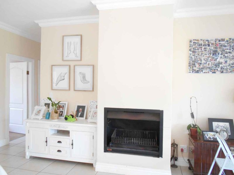 Living area featuring a built-in fireplace, crown molding, and neutral tiled flooring, providing a functional and cozy space.