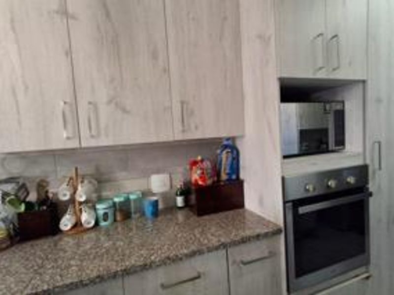 A functional kitchen featuring light wood-grain cabinetry, granite countertops, a tiled backsplash, and integrated oven and microwave appliances.