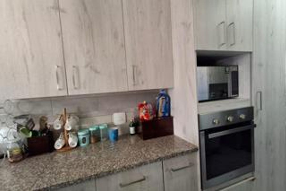 A functional kitchen featuring light wood-grain cabinetry, granite countertops, a tiled backsplash, and integrated oven and microwave appliances.