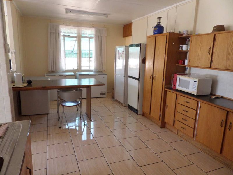 A functional kitchen featuring tiled flooring and traditional wooden cabinetry, offering a practical layout with ample storage space.
