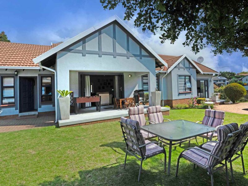 A well-maintained rear exterior view featuring a covered patio, sliding glass doors, and a spacious landscaped garden area.