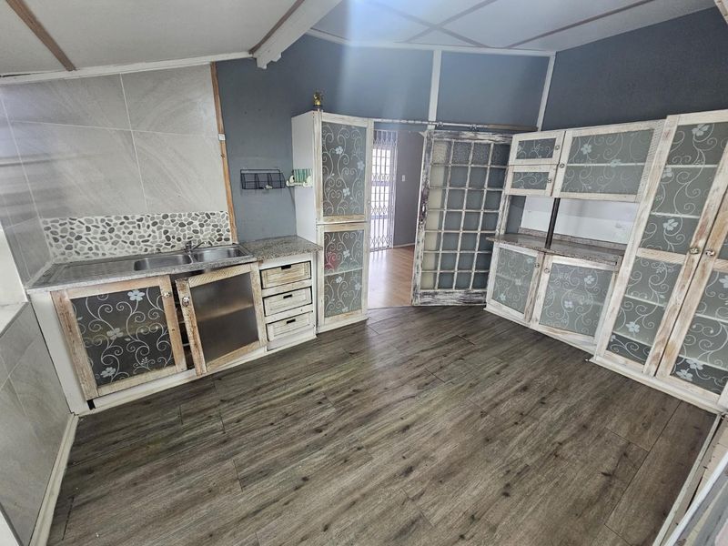 A kitchen area featuring built-in cabinetry, a double sink, and laminate flooring, with a sliding door leading to an adjacent room.