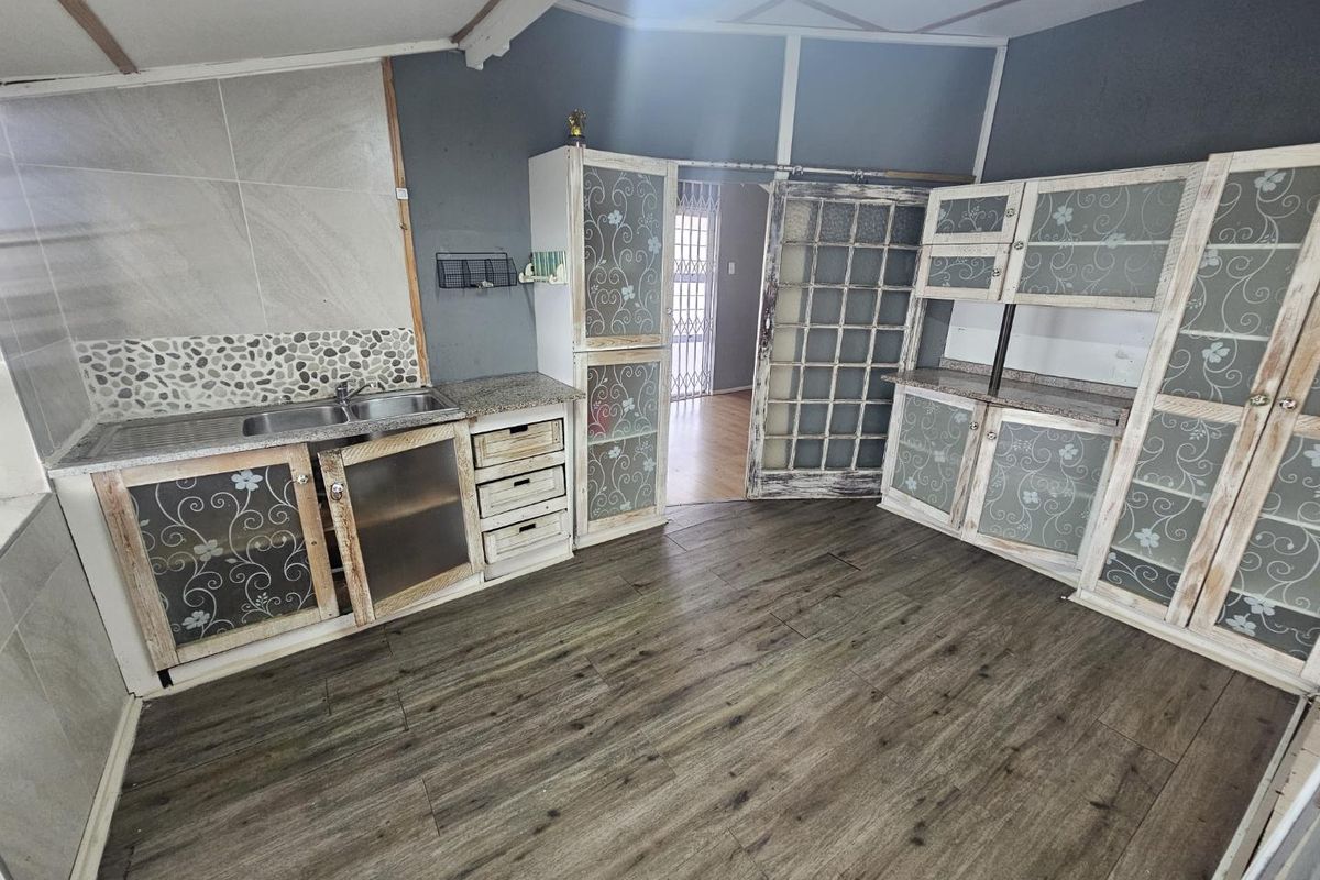 A kitchen area featuring built-in cabinetry, a double sink, and laminate flooring, with a sliding door leading to an adjacent room.